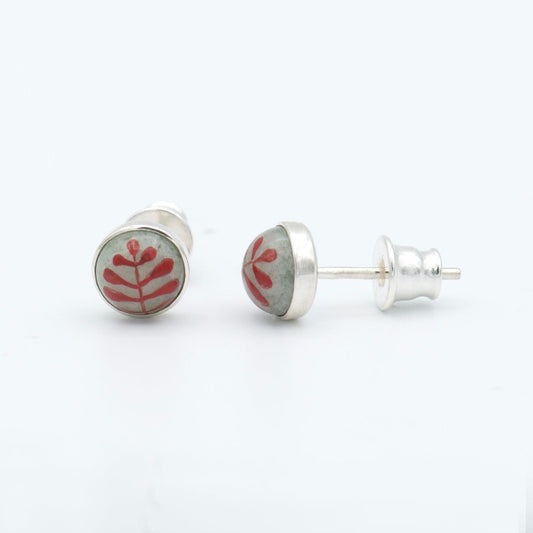 Medium round cabochon studs in sterling silver and glass, featuring a delicate painting of a stylized round leaf. Grey background and red leaf.