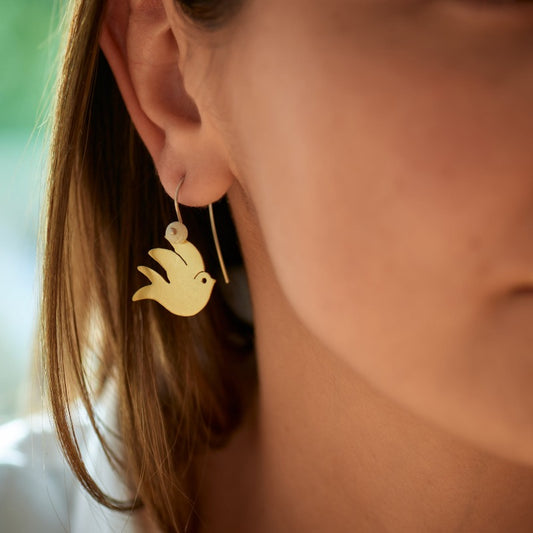 Swallow earrings made from recycled glass, recycled brass and recycled sterling silver. Hand-cut stylised swallow in 18k gold-plated brass, with small handmade glass bead hanging from a sterling silver hook.