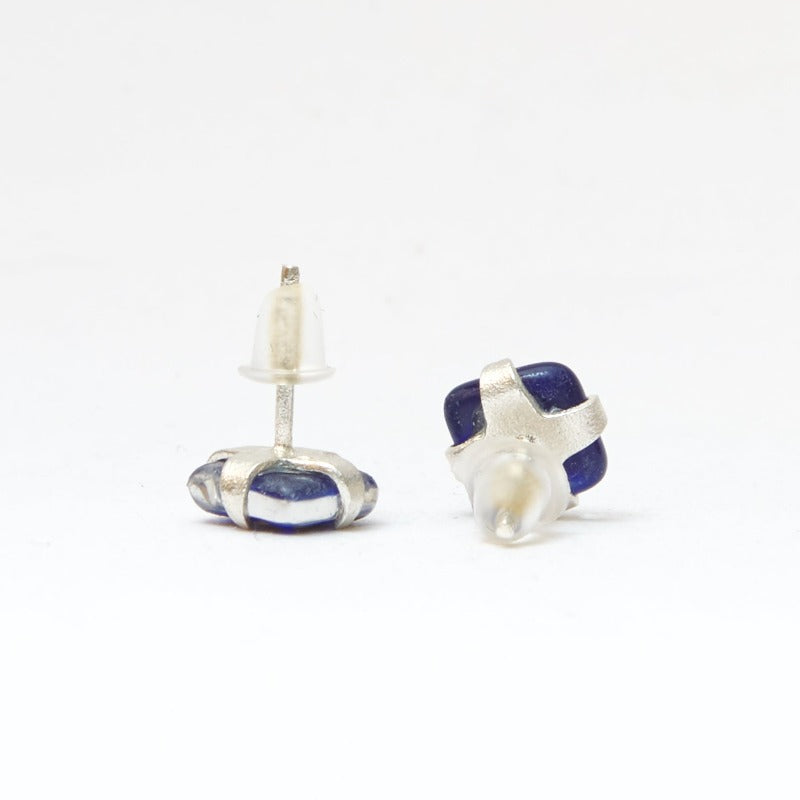 Small square studs crafted with upcycled hand-painted glass, set in sterling silver. Features a botanical pattern for a simple yet elegant design. Blue background and golden leaf.