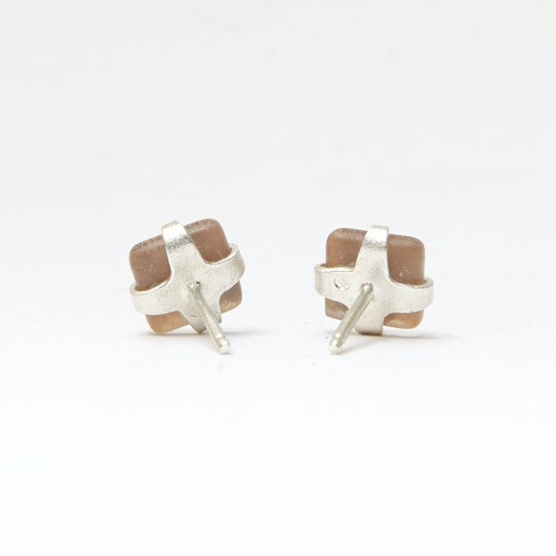 Small square studs crafted with upcycled hand-painted glass, set in sterling silver. Features a botanical pattern for a simple yet elegant design. Golden background and red leaf.