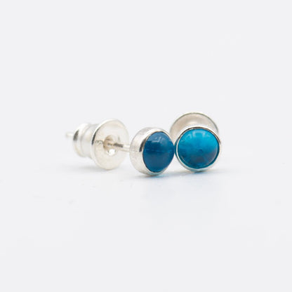 Small round cabochon studs in sterling silver and glass, featuring a tiny upcycled round glass. Translucent blue glass