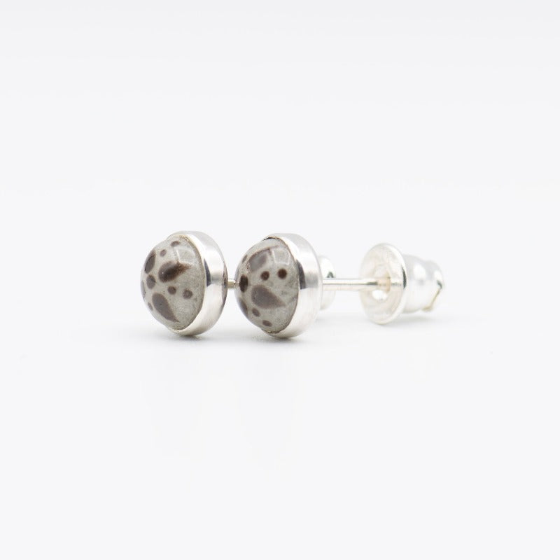 Medium round cabochon studs in sterling silver and glass, featuring a delicate painting of a stylized star. Grey background and brown star.