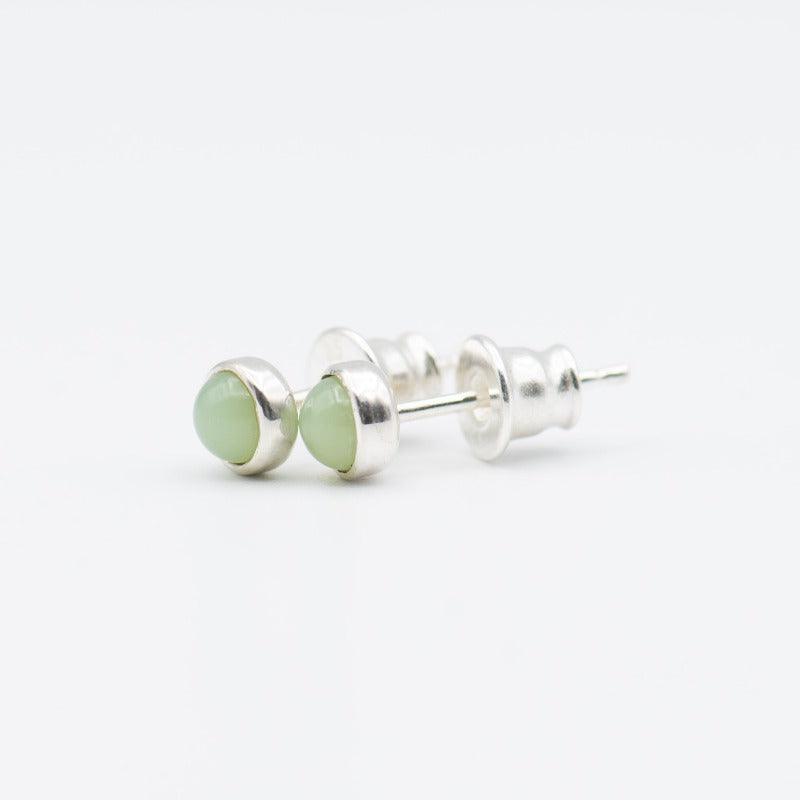 Small round cabochon studs in sterling silver and glass, featuring a tiny upcycled round glass. Light green glass