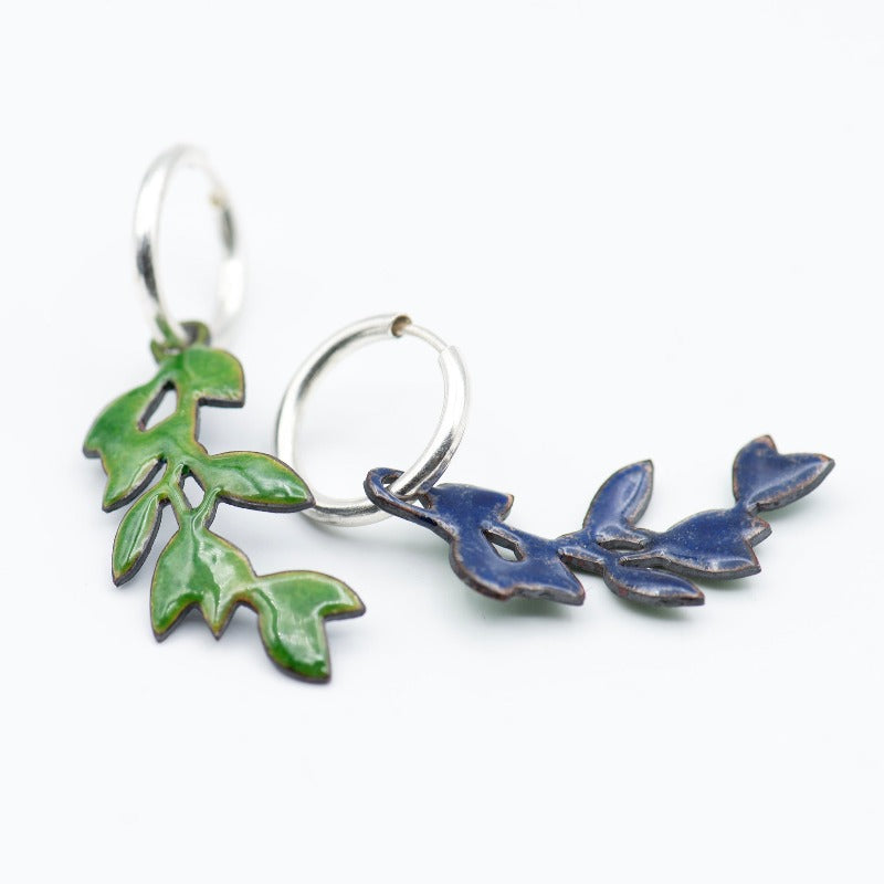 Sterling silver hoop earrings featuring a stylized dangling leafy branch crafted with glass enamel cloisonné on copper. Green colour enamel. Back in a dark blue counter-enamel.