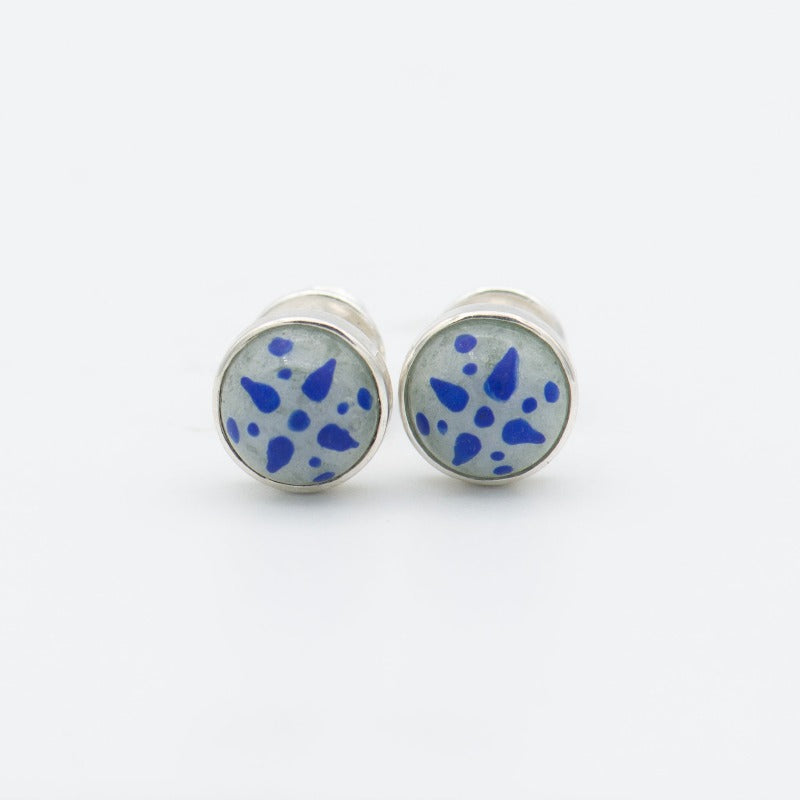 Medium round cabochon studs in sterling silver and glass, featuring a delicate painting of a stylized star. Grey background and blue star.