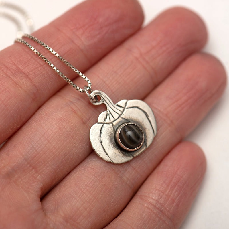 Unique sterling silver pumpkin pendant with hand-cut pumpkin shape and engraved lines, featuring an irreplaceable small glass cabochon setting at the center. Pendant measures approximately 1.8 cm x 2 cm and comes with a 42 cm sterling silver chain with an additional 3 cm of adjustable chain