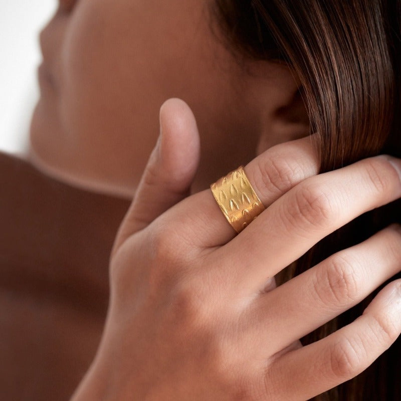 Adjustable, textured wide band brass ring with 18k gold plating, evoking an ethnic vibe inspired by Bronze Age jewelry.