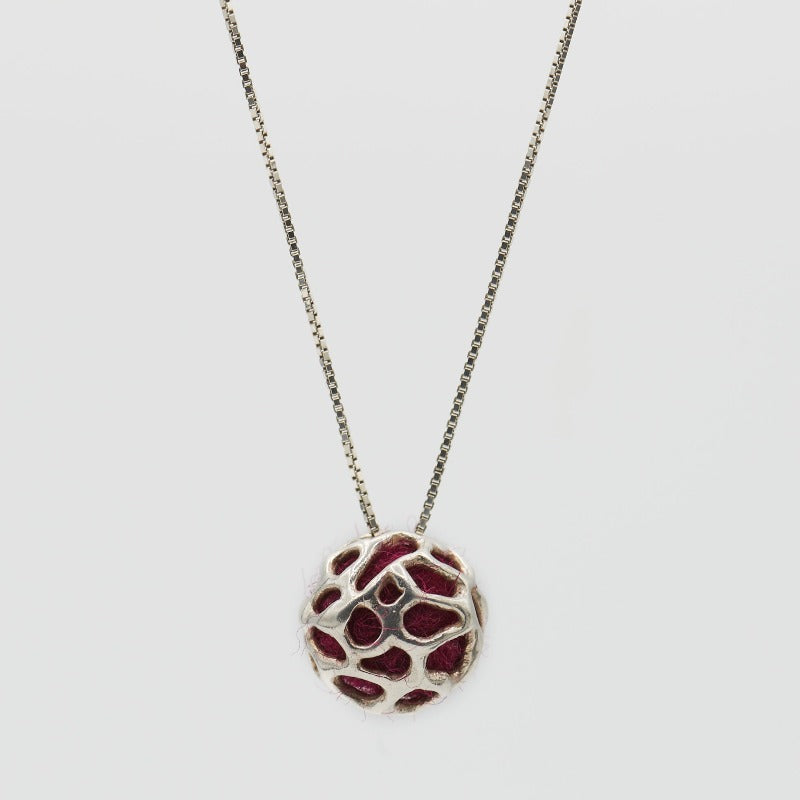 Sterling silver pendant featuring a simple hollow organic shape with colored wool inside, visible through the outer layer. The sphere measures approximately 1.5 cm, paired with a 60 cm sterling silver chain. Red wool