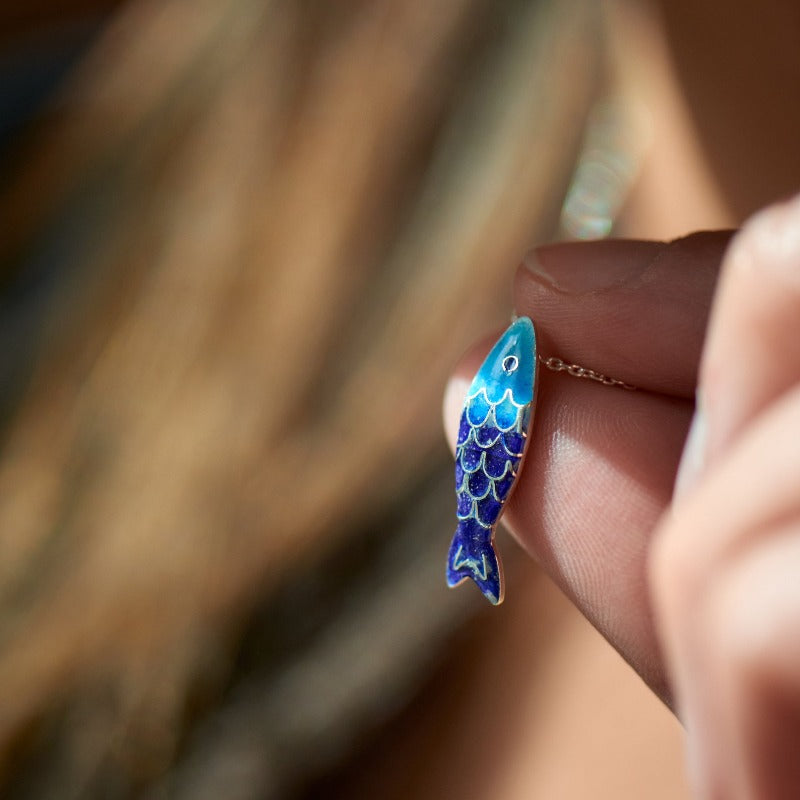 Small glass enamel cloisonné fish, applied on fine silver, accompanied by a delicate 45 cm sterling silver chain with an additional 5 cm for size adjustment. Light blue and dark blue fish.