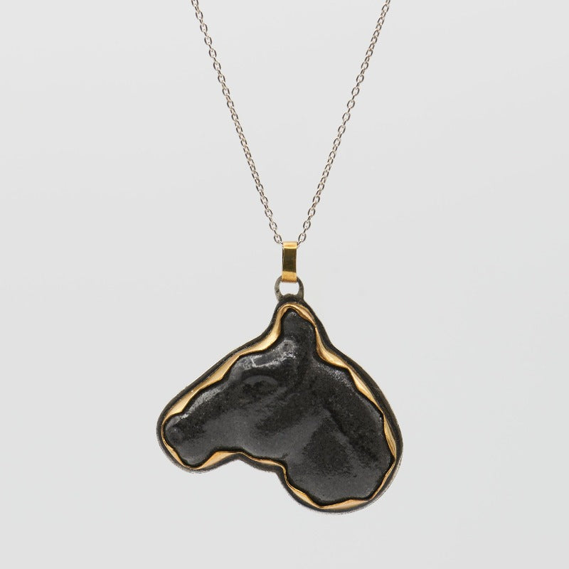 Hand-sculpted glass black horse head framed in brass and sterling silver setting, complemented by a delicate sterling silver chain