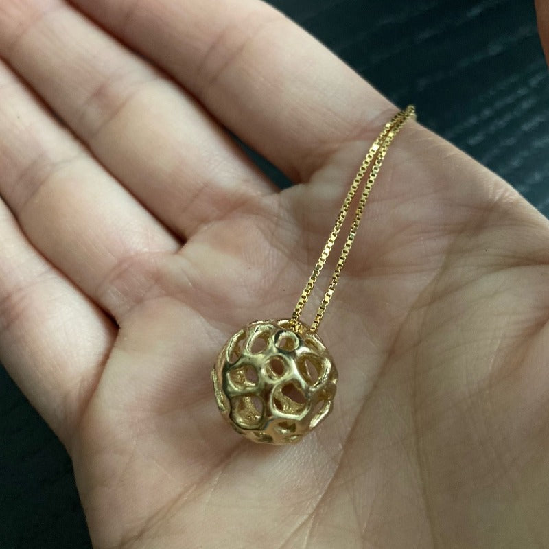 Sterling silver pendant featuring a simple hollow organic shape with colored wool inside, visible through the outer layer. The sphere measures approximately 1.5 cm, paired with a 60 cm sterling silver chain. 18k Gold plated hollow pendant without wool inside